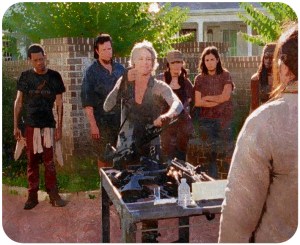 Carol awkwardly gives up her guns, with a smile